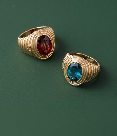 Two gold ribbed birthstone locket rings with garnet and blue zircon stones